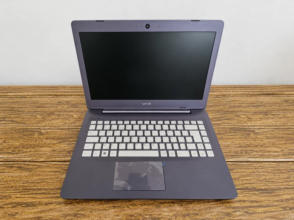 Notebook Vaio i3 de 6ª geração aberto sobre mesa de madeira